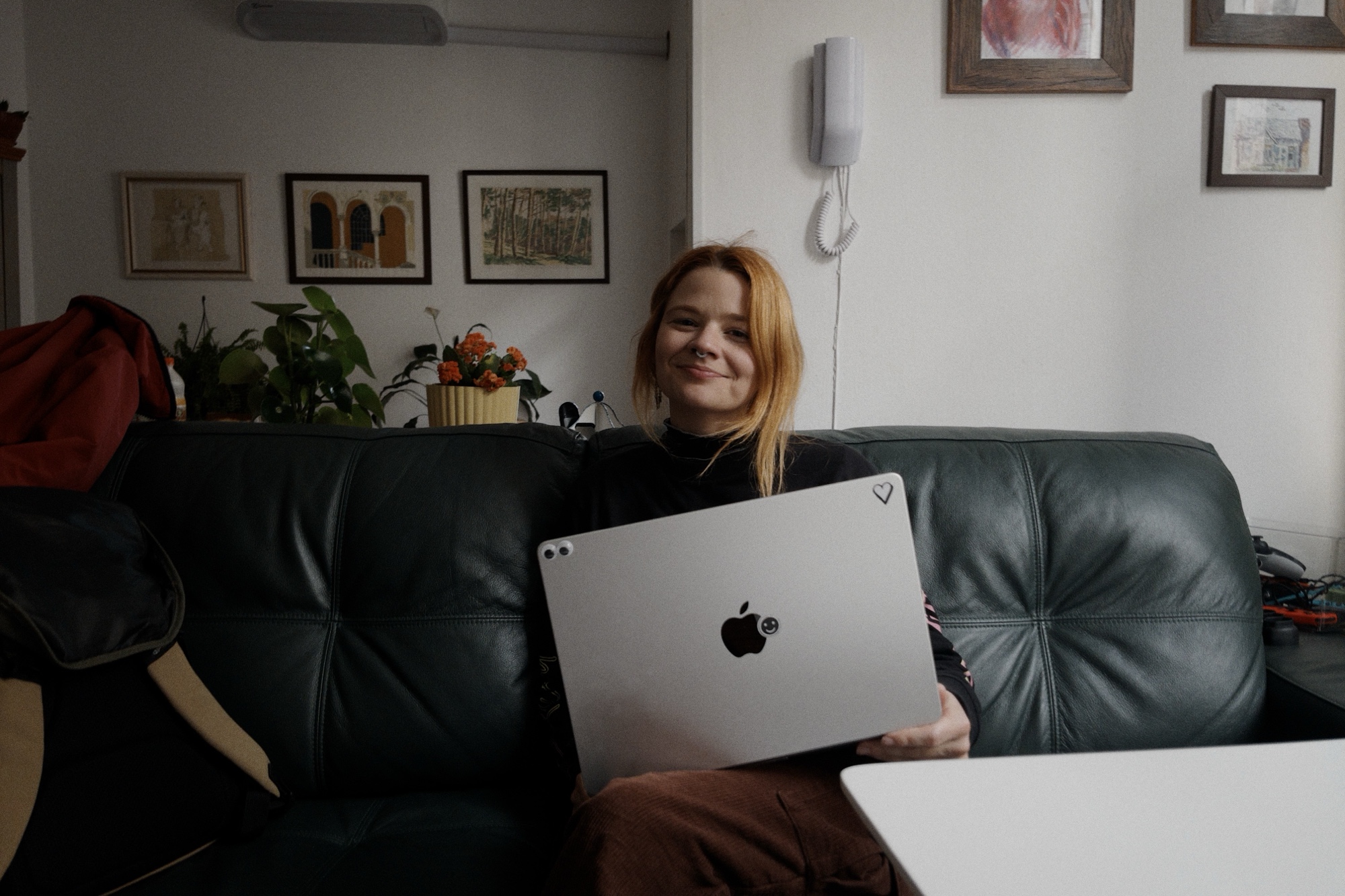 Bruna sentada na sala da minha casa, segurando seu laptop.